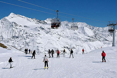 Image of a group of students out on ski slopes in austria, with snowy mountains in the background and ski lifts in the forefront